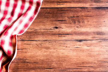 Checkered red napkin on an old wooden brown background, top view. Image with copy space. Kitchen table with a towel - top view with copy space. 