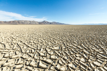 Fototapeta premium Cracked playa mud texture leading out to the mountains on the Black Rock desert