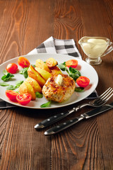 Fried chicken cutlet with potato slices served with tomato cherry and corn salad. Traditional belorussian food - roasted minced meat and potato