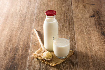 Rice milk in glass and bottle on wooden table. Copyspace