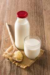 Rice milk in glass and bottle on wooden table. Copyspace