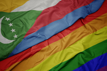 waving colorful gay rainbow flag and national flag of comoros.