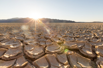 Cracked playa mud texture from the desert to the mountains at sunset