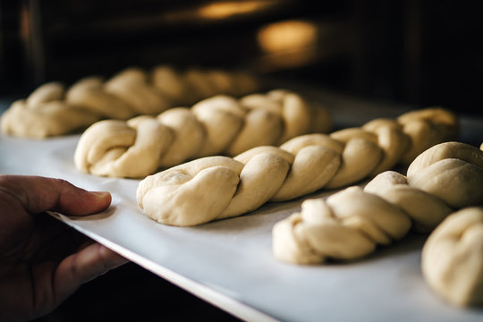 Hand holding sheet with raw braided bread
