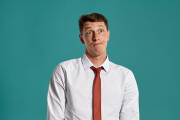 Young man in a classic white shirt and red tie posing over a blue background.
