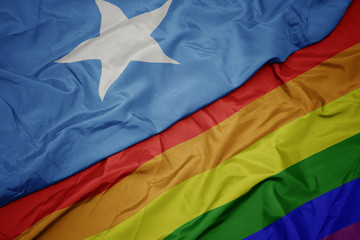 waving colorful gay rainbow flag and national flag of somalia.