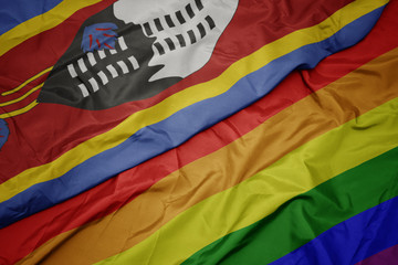 waving colorful gay rainbow flag and national flag of swaziland.