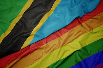 waving colorful gay rainbow flag and national flag of tanzania.