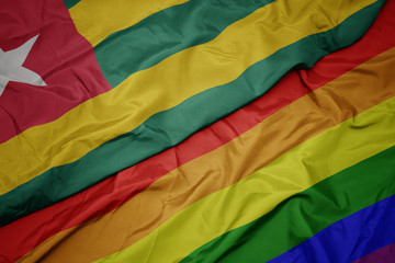 waving colorful gay rainbow flag and national flag of togo.