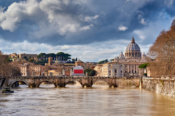 Fototapeta premium St. Peter's cathedral and Tiber river with high water in February. Saint Peter Basilica in Vatican city with Saint Angelo Bridge in Rome, Italy
