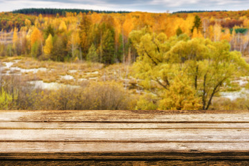 Naklejka na ściany i meble Empty wooden table with blurred picturesque autumn landscape of view from the hill to the lowland with forest and swamps. Mock up for display or montage products