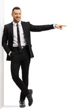 Businessman leaning on a wall and pointing to the side