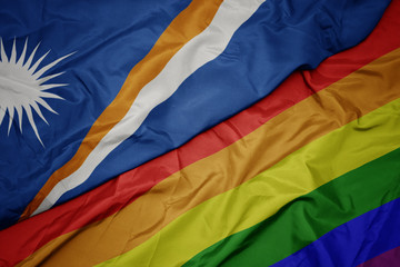 waving colorful gay rainbow flag and national flag of Marshall Islands.