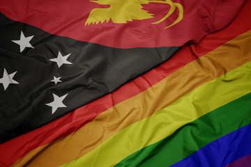 waving colorful gay rainbow flag and national flag of Papua New Guinea.