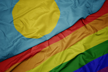 waving colorful gay rainbow flag and national flag of Palau