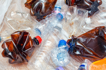 Lot of used plastic, crumpled empty bottles, packets, plastic orange dish, diaper, pollution recycle eco concept background close up selective focus