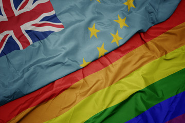 waving colorful gay rainbow flag and national flag of Tuvalu .