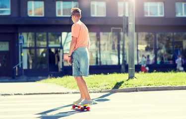 Plakat summer, traffic, extreme sport and people concept - teenage boy riding short modern cruiser skateboard on crosswalk in city