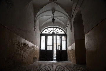 Empty gloomy arch of an old house with light on exit. 