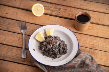 Plate of black rice with squid and prawns or Valencian black paella