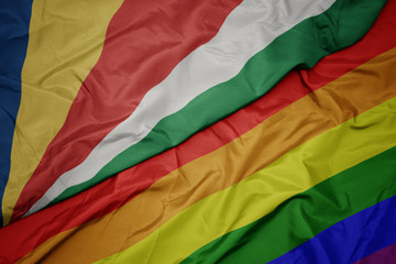 waving colorful gay rainbow flag and national flag of seychelles.