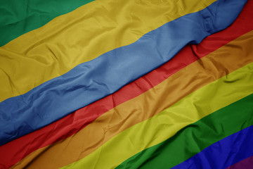 waving colorful gay rainbow flag and national flag of gabon.