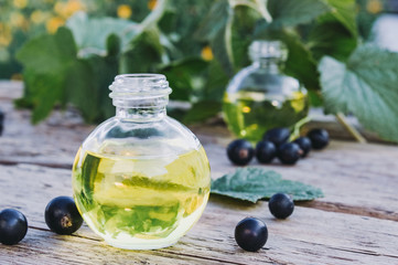 Black currant oil in a bottle on the background of old boards. Cold remedy extract of black currant.