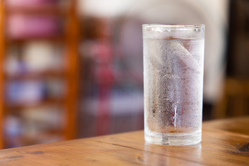 A glass of cold water on a wooden table.