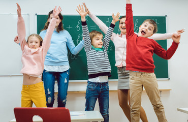 Fototapeta premium Teacher and students of primary school jumping in classroom