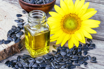 Sunflowers and seeds on a wooden background near sunflower oil in a glass jar. Healthy foods and...