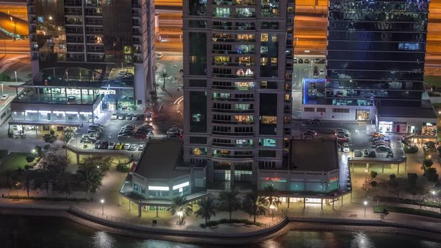 Residential and office buildings in Jumeirah lake towers district night timelapse with shops, restaurants and walkways in Dubai. Aerial panoramic view from above with modern skyscrapers