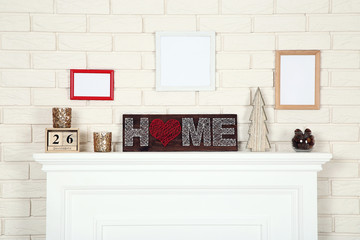 White fireplace with photo frames, word Home and wooden fir tree