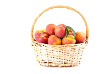 Fresh peaches with green leafs in basket isolated on white background