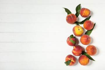 Fresh peaches with green leafs on white wooden table