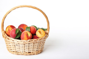 Fresh peaches in basket on white wooden table