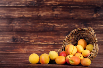 Sweet apricots in basket on brown wooden table