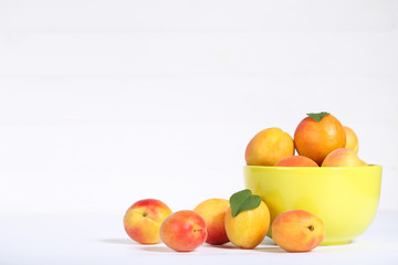 Sweet apricots in bowl on white background