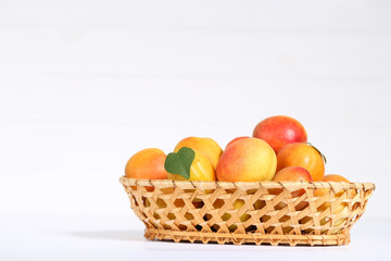 Sweet apricots in basket on white background