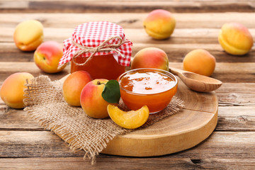 Apricot jam in bowl and jar on brown wooden table