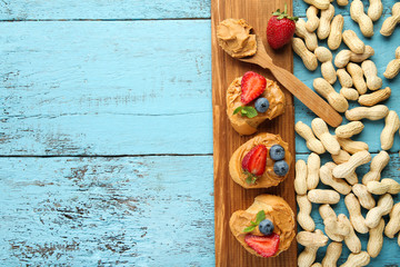 Bread with peanut butter, fruits and nuts on wooden table