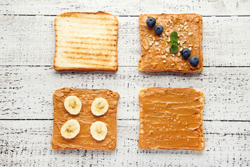 Bread with peanut butter, fruits and nuts on wooden table