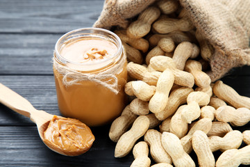 Peanut butter and nuts in sackcloth on black wooden table