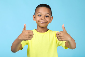 Cute american boy showing thumb up on blue background