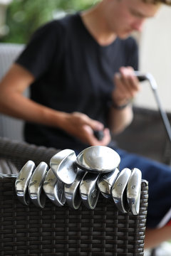 A Young Golfer Cleans His Golf Clubs