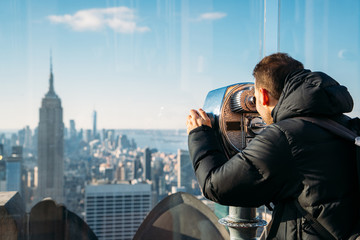 A boy observing New York City through a telescope