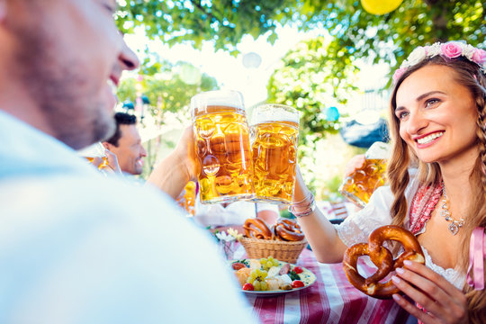Couple clinking glasses with huge amounts of beer in Bavarian pub