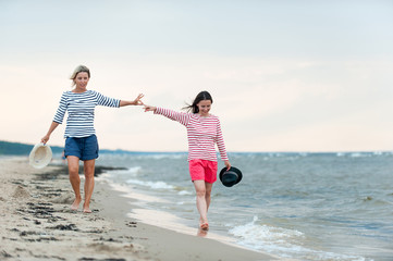 Two young women walking together on the seaside holding hands