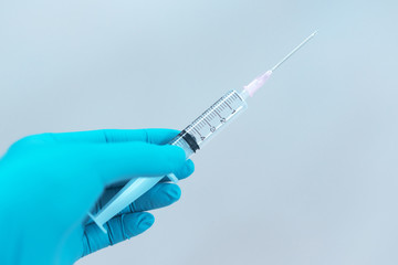 The doctor wore blue gloves, holding a needle in the hospital.