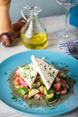 greek salad with chunk feta cheese on blue plate