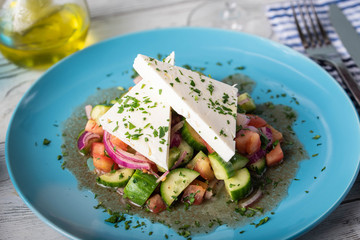 greek salad with chunk feta cheese on blue plate